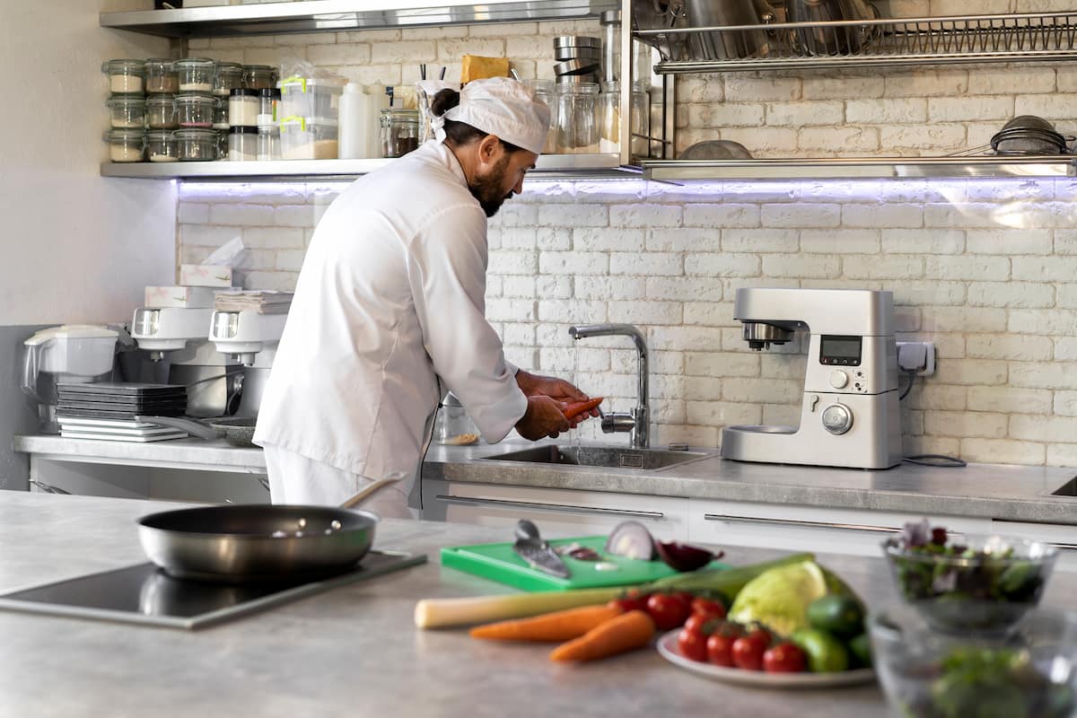 Un chef en una cocina lavando zanahorias, representando el modelo de negocio dark kitchen enfocado en la eficiencia culinaria.