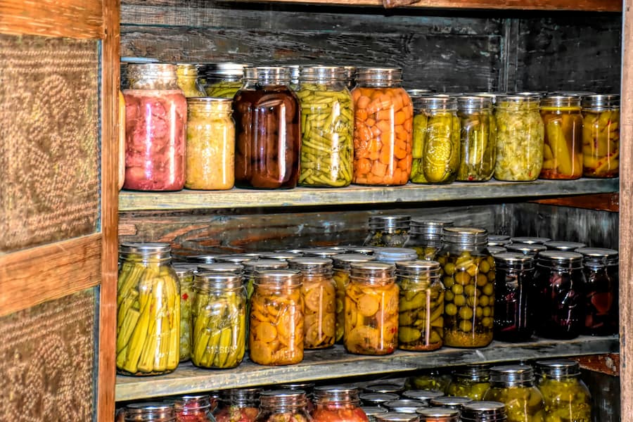 Alimentos envasados en frascos en un estante de madera.