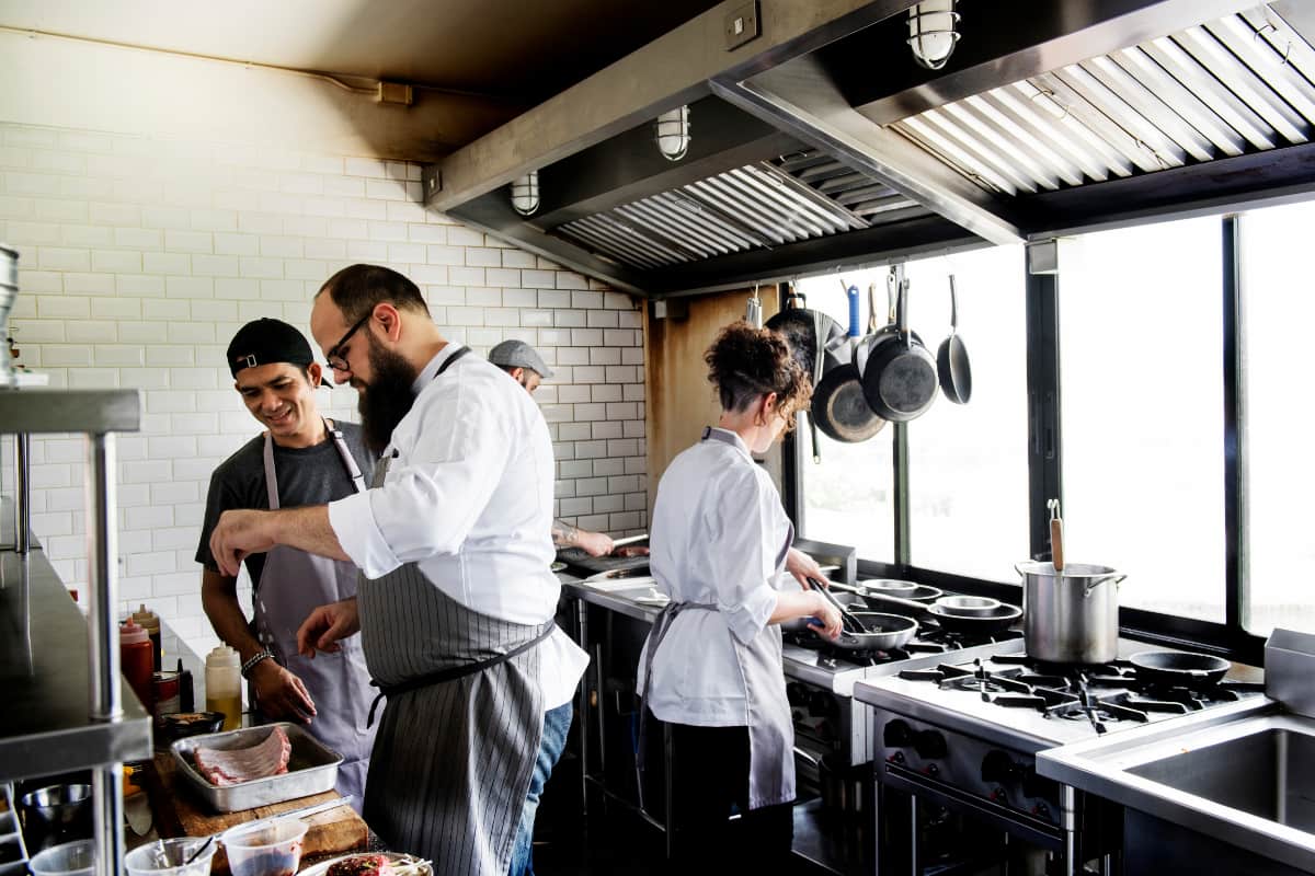 Chefs trabalhando em uma cozinha moderna, mostrando diferentes tipos de dark kitchen, com foco em eficiência e operação otimizada.
