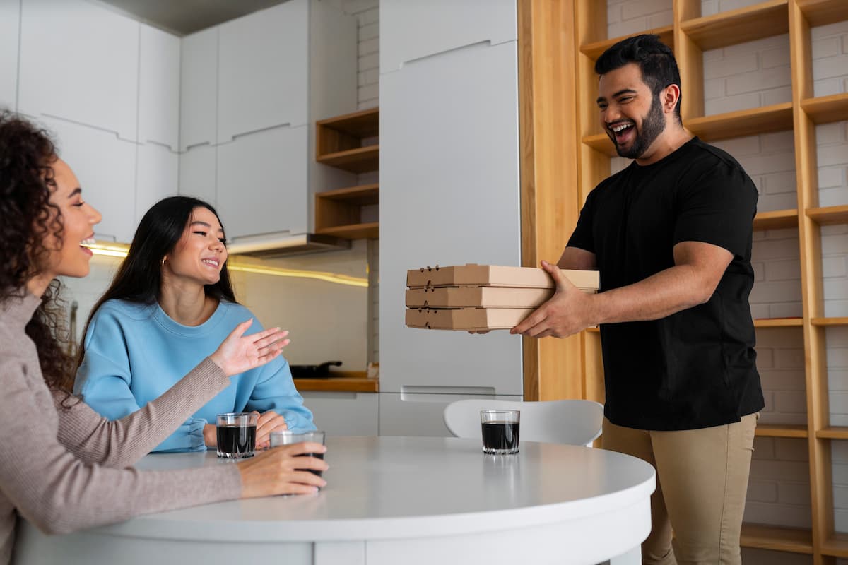 Repartidor entregando pizzas con una sonrisa, ejemplo de cómo realizar entregas exitosas en épocas de alta demanda.