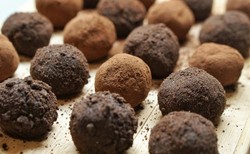 Brigadeiros de café com diferentes coberturas, apresentados em uma tábua de madeira
