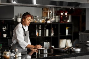 Mujer en uniforme de chef cocinando en una cocina, ilustrando la elección de una dark kitchen para negocios gastronómicos.