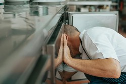 Cozinheiro limpando a área interna de uma geladeira na cozinha