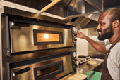 Cozinheiro ajustando a temperatura do forno da cozinha para delivery