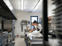 A imagem mostra o interior de uma cozinha profissional, que pode ser identificada como uma dark kitchen (ou cozinha fantasma), um modelo de negócio voltado exclusivamente para entregas.