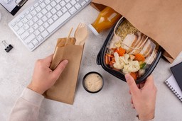 Pessoa abre embalagem de marmita saudável no escritório, ilustrando como resolver uma operação de delivery travada.