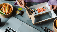 A imagem retrata uma cena de refeição rápida ou "delivery" em um ambiente de trabalho, focada em comida japonesa .