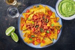 Nachos con carne, tomates y jalapeños, acompañados de guacamole, un excelente snack para vender en delivery.