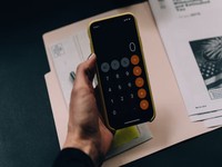 En la imagen vemos a una persona trabajando sobre una mesa con diferentes elementos: moldes de empaques, planos técnicos, una tablet, carpetas con material visual y utensilios de diseño. El entorno transmite un ambiente de planificación, diseño y análisis.