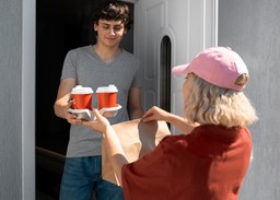 Entregador passando pedido para cliente; bom atendimento é essencial em como lidar com as reclamações do cliente no delivery.