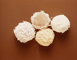 Brigadeiros de coco exibidos em uma bela composição sobre um fundo marrom