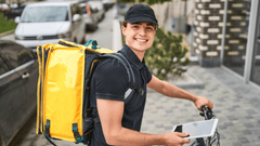 Esta imagen muestra a un repartidor de comida joven y sonriente mientras se prepara para realizar una entrega.