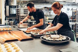 Chefs preparando pratos variados em uma cozinha de catering.