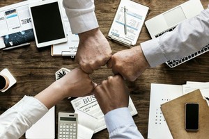 Manos de 4 personas saludándose en el centro de una mesa.