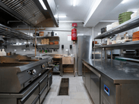 A imagem mostra o interior de uma cozinha industrial ou profissional, projetada para alta eficiência, o que é característico de uma Dark Kitchen (cozinha fantasma), conforme sugere o nome do arquivo.