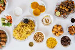 Variedade de pratos de comida árabe, incluindo falafel, kebabs e doces coloridos.