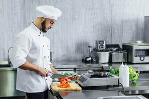 Chef preparando alimentos en una cocina comercial, destacando la importancia de elegir la mejor dark kitchen para negocios gastronómicos.