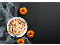 La imagen muestra una escena decorativa de Halloween con un plato lleno de galletas en forma de dedos de bruja. Las galletas tienen almendras como uñas y están rodeadas de caramelos de gelatina de colores.