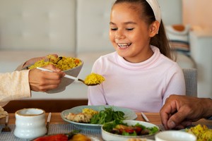 Niña feliz recibiendo su comida como parte de un menú especial para delivery en el Día del Niño.