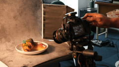 Os bastidores de um ensaio fotográfico de alimentos em um estúdio improvisado ou técnico.