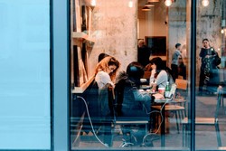 Un grupo de personas colaborando en una cafetería. Están sentadas alrededor de una mesa, trabajando en laptops y disfrutando bebidas. El ambiente refleja un espacio dinámico y comunitario para trabajo en equipo y conexión social
