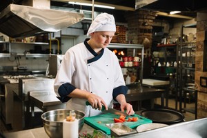 Chef en uniforme blanco picando tomates, ilustrando casos de éxito de dark kitchens en Latinoamérica.