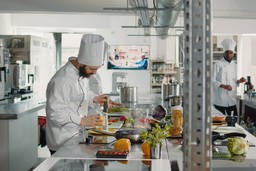Chefs preparam pratos em cozinha profissional, representando como planejar a operação de dark kitchens para datas comemorativas.