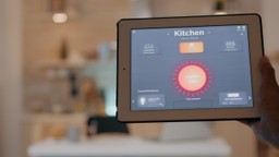 O que é smart kitchen: homem segurando um-tablet com aplicativo de controle de iluminação acendendo as luzes da cozinha