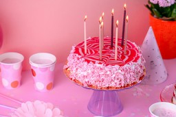 Delicioso bolo decorado com cobertura rosa e velas, ideal para explorar sabores de bolo de aniversário em celebrações especiais.