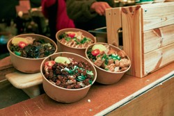 Quatro tigelas biodegradáveis cheias de alimentos frescos e coloridos, como vegetais, carnes e acompanhamentos.