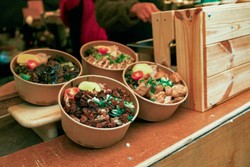 Quatro tigelas biodegradáveis cheias de alimentos frescos e coloridos, como vegetais, carnes e acompanhamentos.