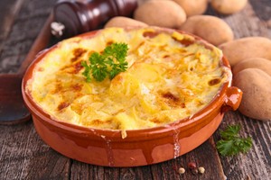 Gratinado de papas con queso dorado, servido en cazuela rústica, ideal para recetas con papa para delivery.