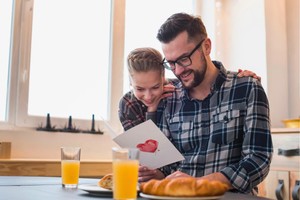 Padre e hija celebrando con desayuno y tarjeta: inspiración para estrategias de restaurantes para el Día del Padre.