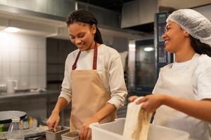 Dos mujeres con delantales trabajando en una cocina, representando casos de éxito de dark kitchen en Latinoamérica.