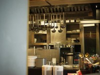 A imagem mostra uma cozinha comercial moderna e bem organizada, possivelmente em um restaurante profissional.