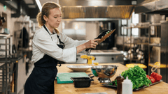 Esta imagen muestra a una joven chef trabajando con mucha concentración en una cocina profesional.