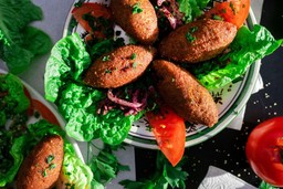 Vários quibes dentro de um prato com salada.