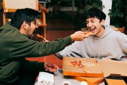 Dos amigos divirtiéndose mientras comparten una deliciosa pizza, con risas