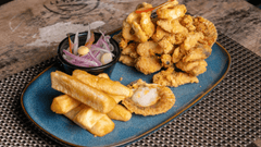 Esta imagen muestra un plato clásico y delicioso de la gastronomía peruana conocido como Jalea Mixta. Es un festín de texturas crujientes y sabores frescos.