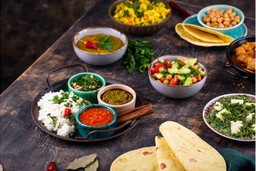Festival de sabores da comida indiana: Thali tradicional com arroz, lentilhas, legumes e especiarias em uma tábua de cobre.