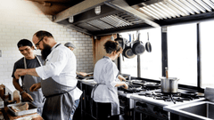 La imagen muestra a un equipo de cocineros trabajando de forma coordinada en una cocina profesional.