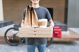 Entregador com pizzas e bebidas em sacolas de papel, exemplificando recuperação de vendas no delivery com foco em conveniência.